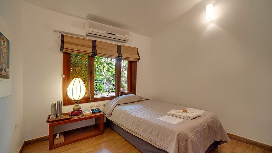 A bedroom with a low bed, a window with blinds, and a lamp - Shreyas Retreat