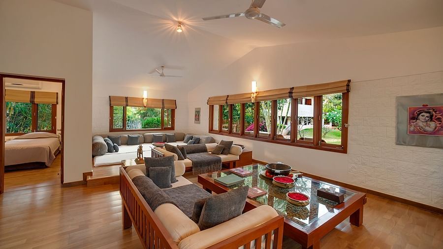 A living room with a couch, armchairs, a coffee table, and large windows - Shreyas Retreat