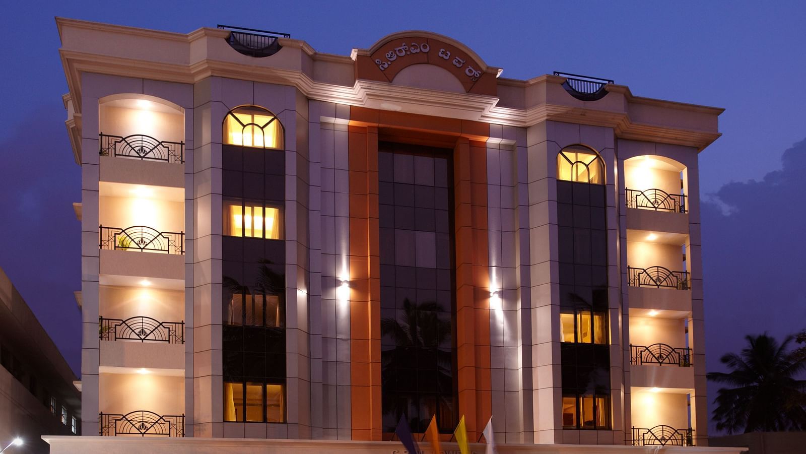 Grand facade of The President Hotel Jayanagar, Bangalore with striking red accents and a majestic entrance, showcasing a blend of traditional and contemporary architecture