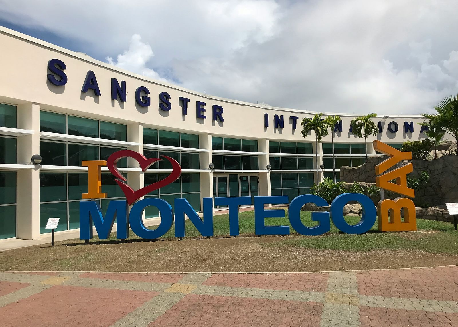 A signage of Montego Bay in front of the local airport with a walking path in front of the signage.