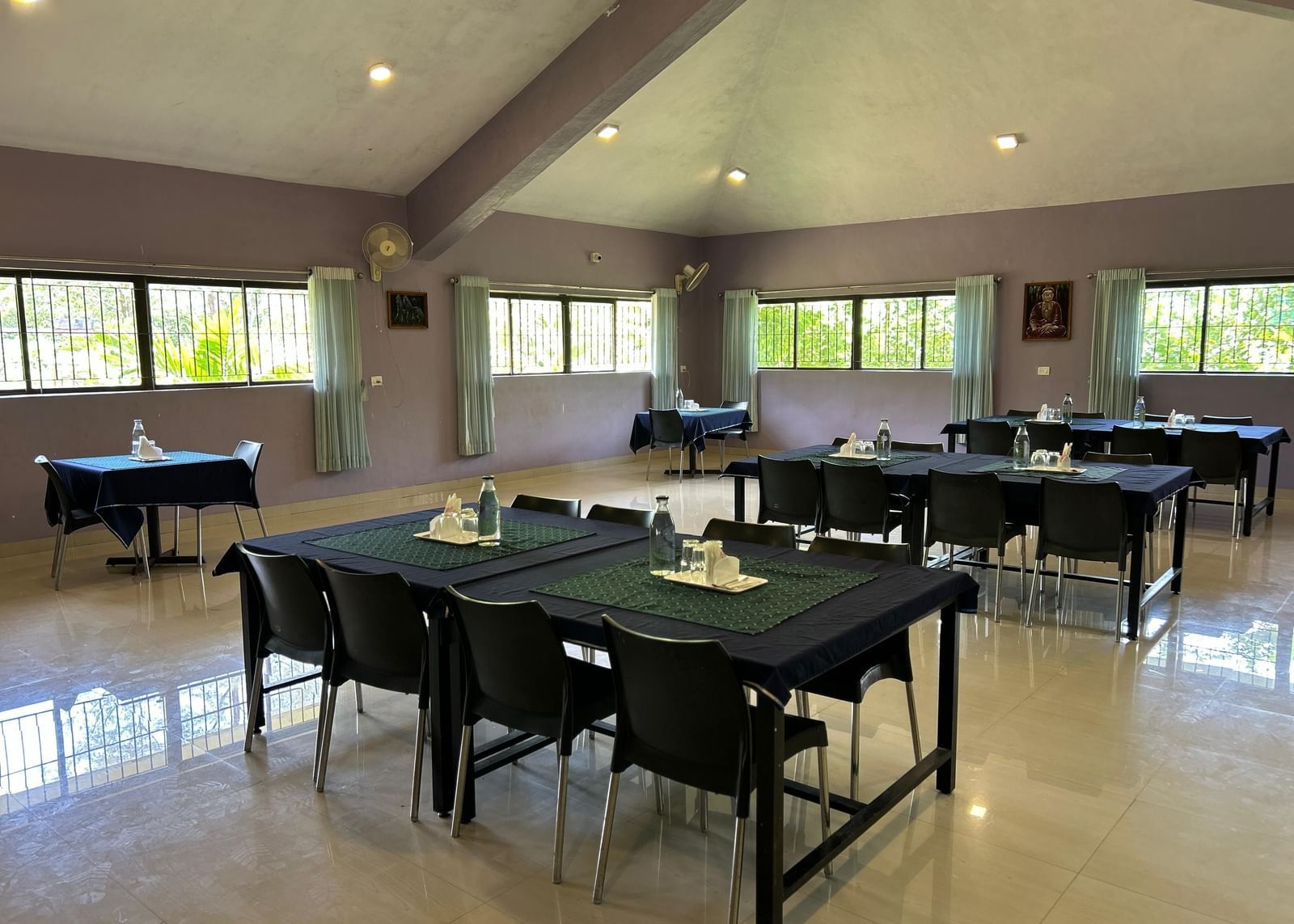 Dining hall with black tablecloth-covered tables and chairs arranged in rows at Paradise Wild Hills Resort, Kollur.