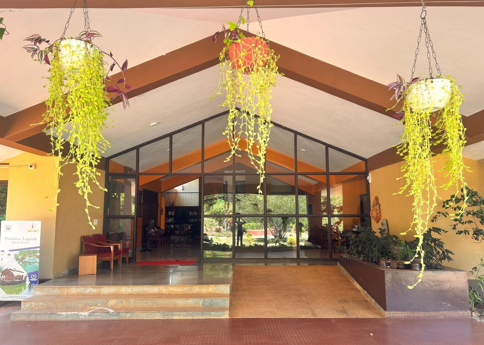 The beautiful main entrance to Paradise Wild Hills Resort, Kollur, with hanging plants and large glass doors.
