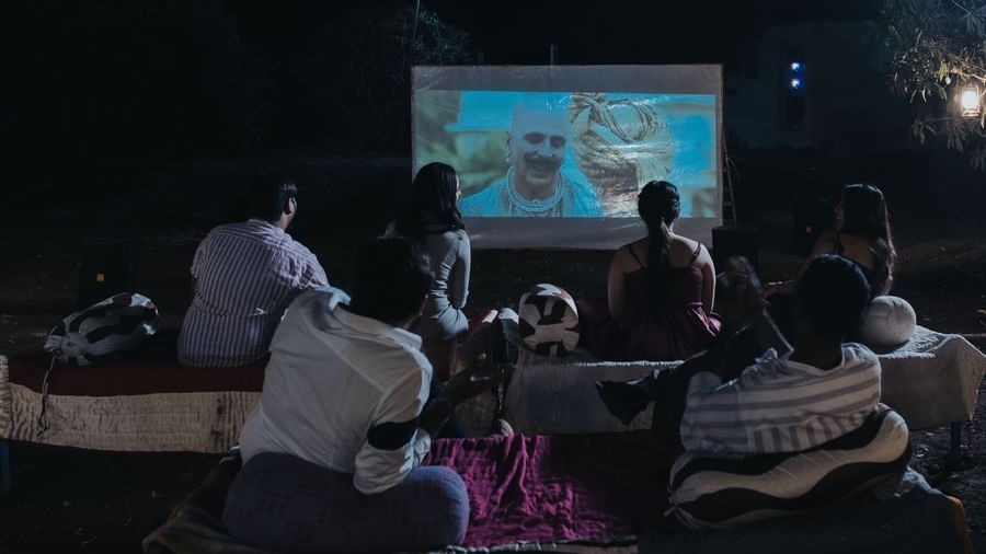 Guests seated under the night sky enjoying an open-air movie screening on a large projector screen at Daksh Resort and Amusement Park.