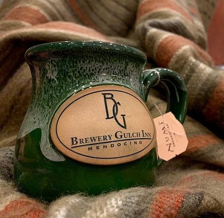 A mug with a logo rests on a patterned fabric.