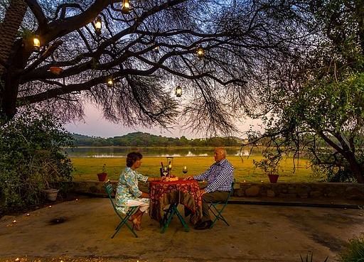 a couple enjoying an open air romantic dinner with a beautiful sunset in the background at Dev Shree, Deogarh
