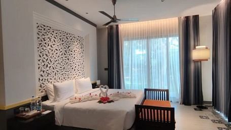 A bedroom featuring a flower-patterned headboard and white sheer curtains.