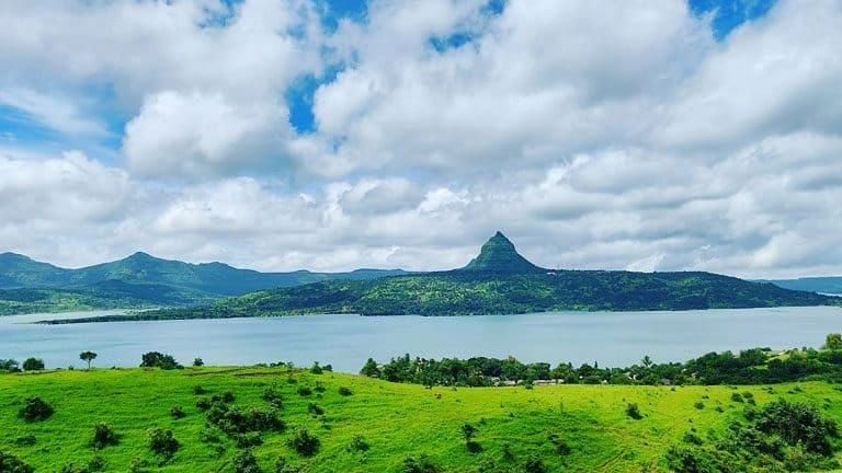 Scenic view of rolling hills and a lake under a blue sky.