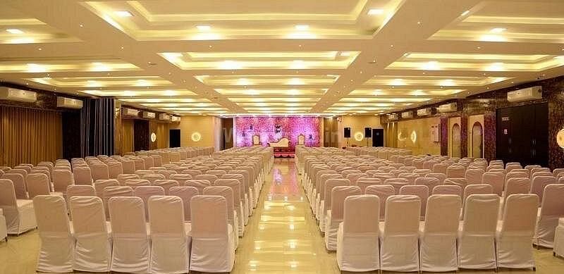 Large, empty hotel conference room with rows of white chairs - Shyanu Lords Eco Inn Airoli