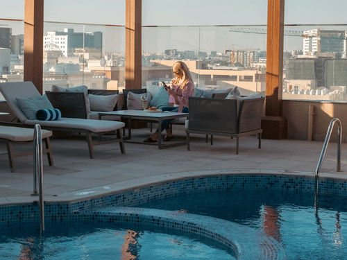 Poolside seating with patio and city views at La Maison Hotel, Doha.