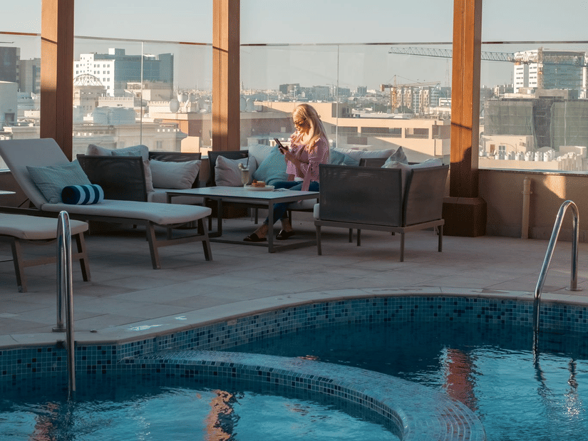 Poolside seating with patio and city views at La Maison Hotel, Doha.