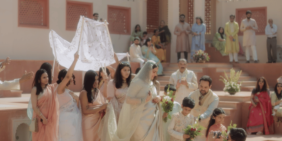 Bride descending red sandstone steps under a draped white canopy at Umaid Palace.