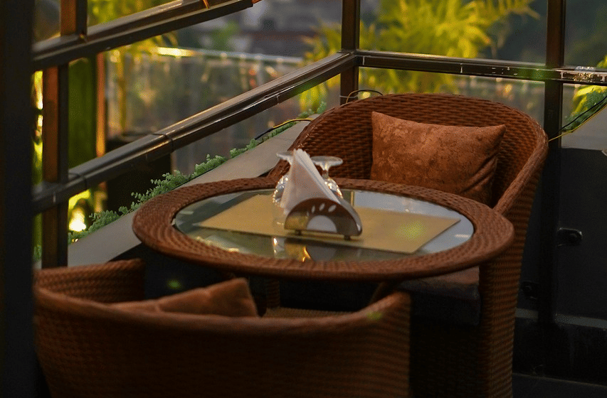 Two chairs facing each other on a terrace with warm lights besides it on a late evening.