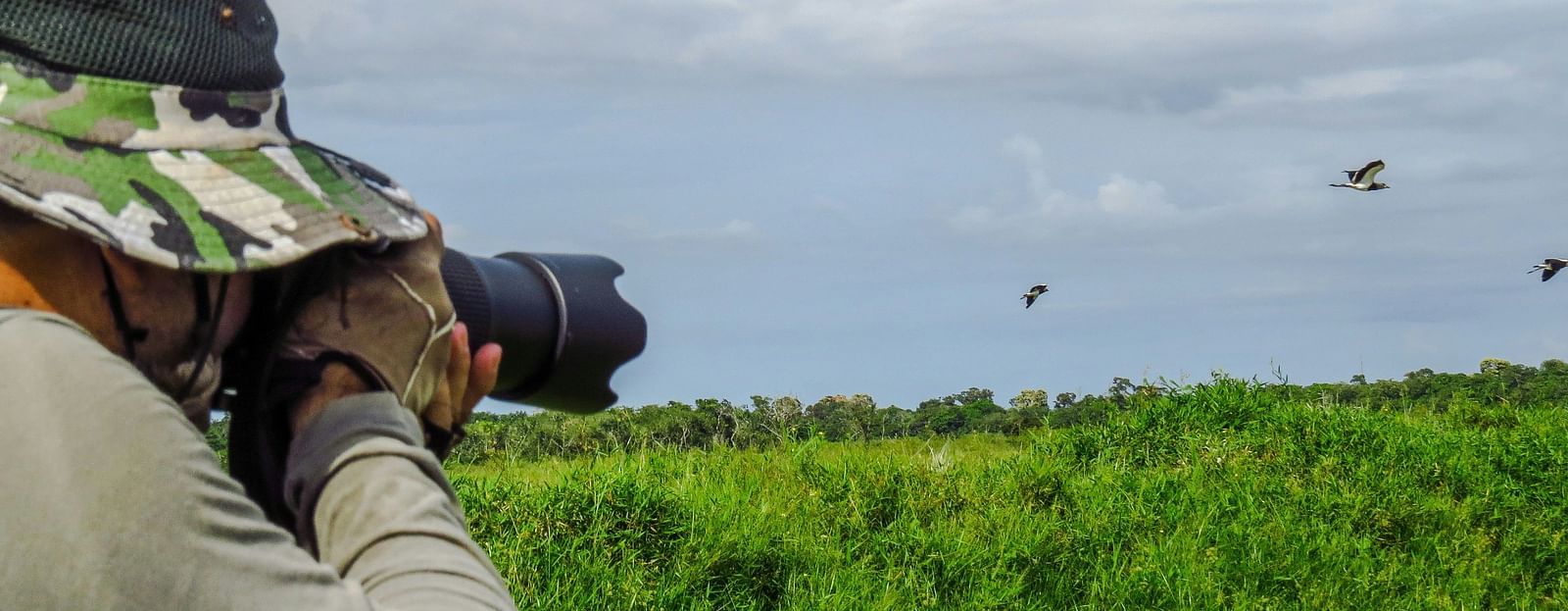 Side view of a man wearing a hat with a camera in hand.