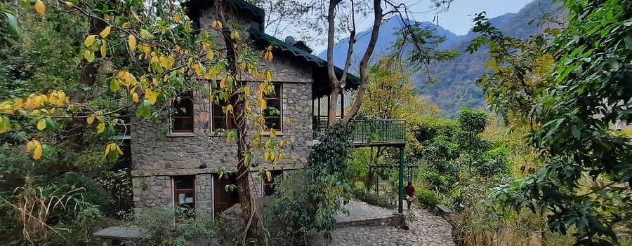 Facade view of Glasshouse on the Ganges amidst the nature with mountains and clear blue sky in the background.