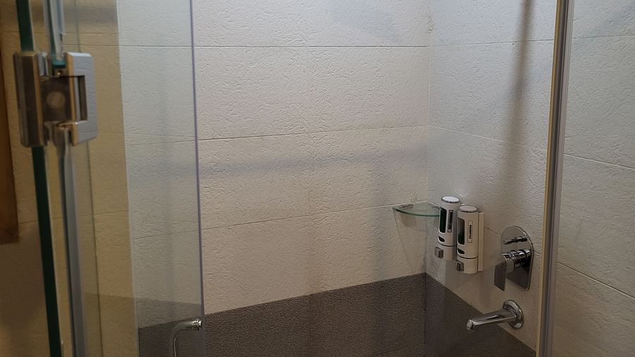 A glass-enclosed shower area with a rainfall shower head and modern fixtures at Dagshai Manor Kasauli - Inde Hotels.