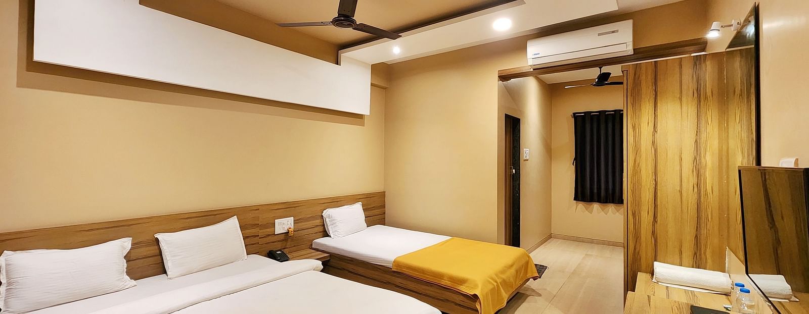 Triple Premium Room at The Kanila Resort featuring a bed with a gray headboard and white sheets and curtains.