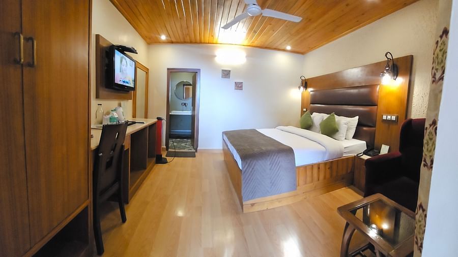 A full view of a room with a bed, TV, and other furniture | Mongas Hotel & Resort, Dalhousie