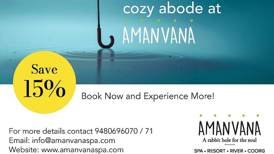 Orange umbrella in rain with water droplets against blue sky, advertising Amanvana Spa Resort, Coorgs monsoon experience with 15% discount offer