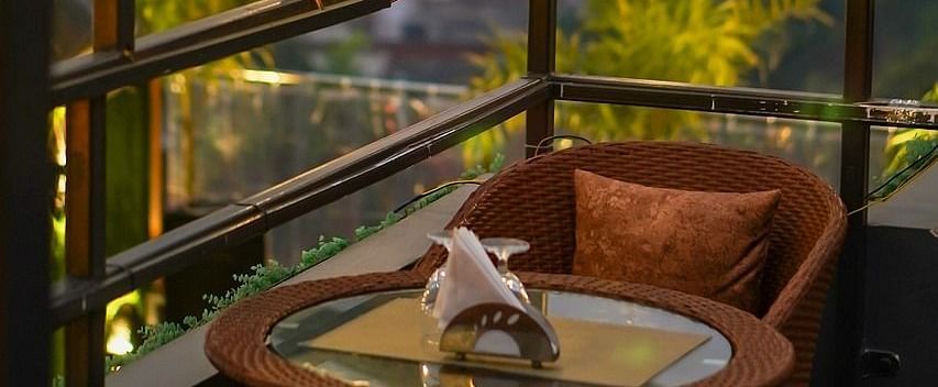 Two chairs facing each other on a terrace with warm lights besides it on a late evening.