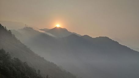 mountain peaks under a bright sunraise and foggy sky.