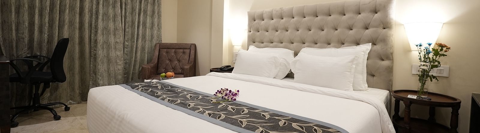 Modern hotel room with a work desk, large bed, and grey curtains at The Verda de Miranda Resort.