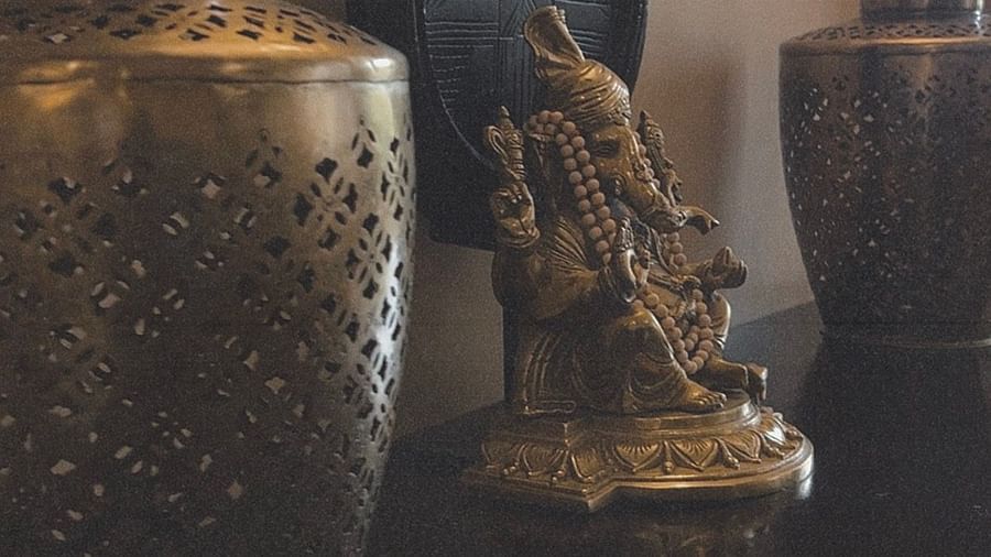  A close-up of cultural decor, including a metal pot and a figurine on a wooden surface.