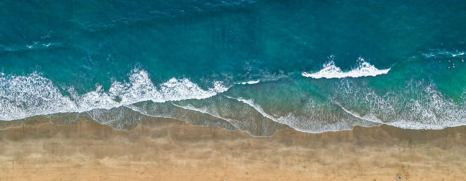 an aerial view of waves overlapping on the beach on agonda beach.