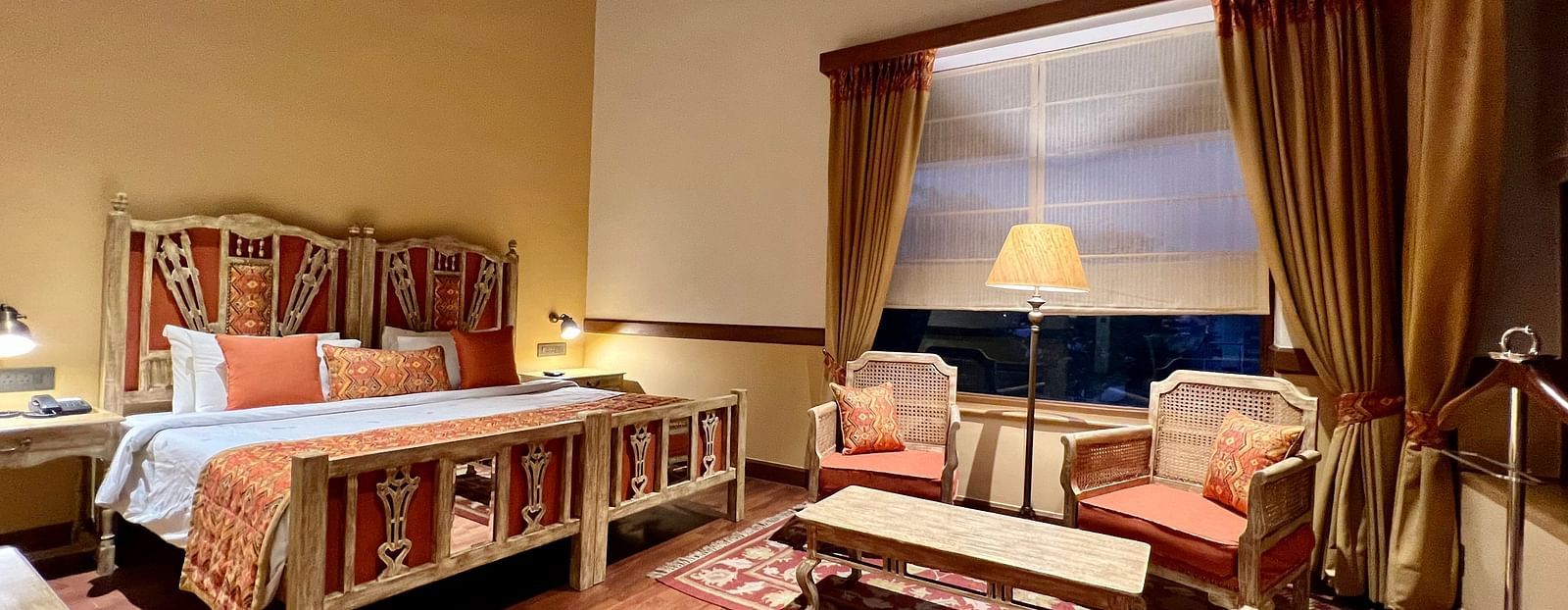 A cozy Superior Lake Facing Room at Fishermen's Lodge, Bhimtal, featuring a comfy bed, sofa, and table, perfect for relaxation.