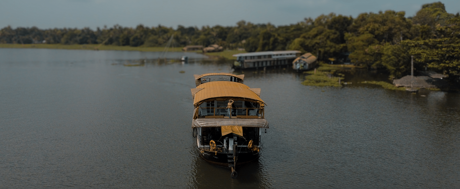 A cruise sailing across the Vembanad Lake with lush greenery in the background - BluSalzz Villas - Muhamma Resort, Alleppey