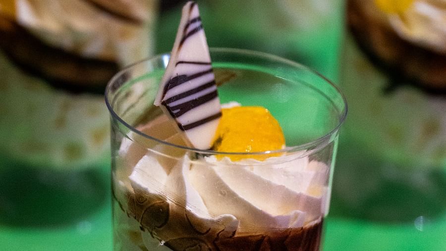 A dessert in a glass with a spoon, featuring layers and a garnish.