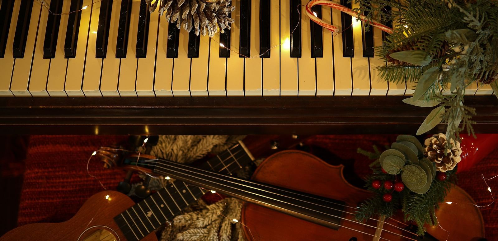 An overhead shot of piano and violin arrangement decorated with pine cones and leaves.