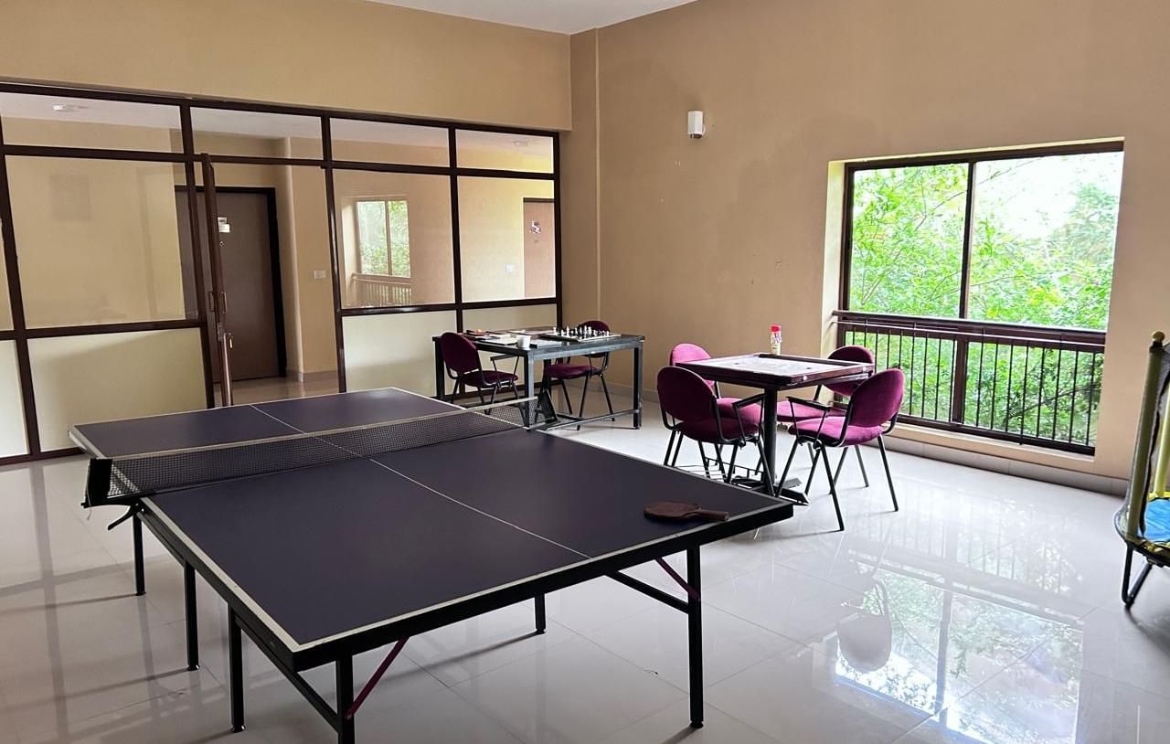 The recreational room at Paradise Wild Hills Resort, Kollur, with a table tennis table and a seating area.
