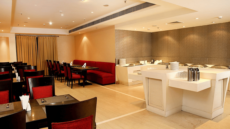 The restaurant at Eastlynn Collections Huda City Centre, Gurugram, features red chairs and a central food island.