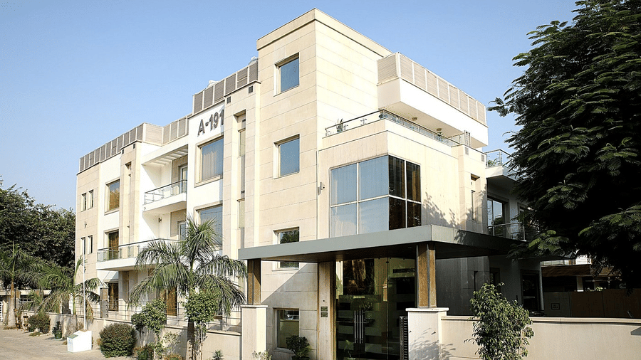 Palm trees flank the entrance of the Eastlynn Collections Huda City Centre, Gurugram, building during the daytime.