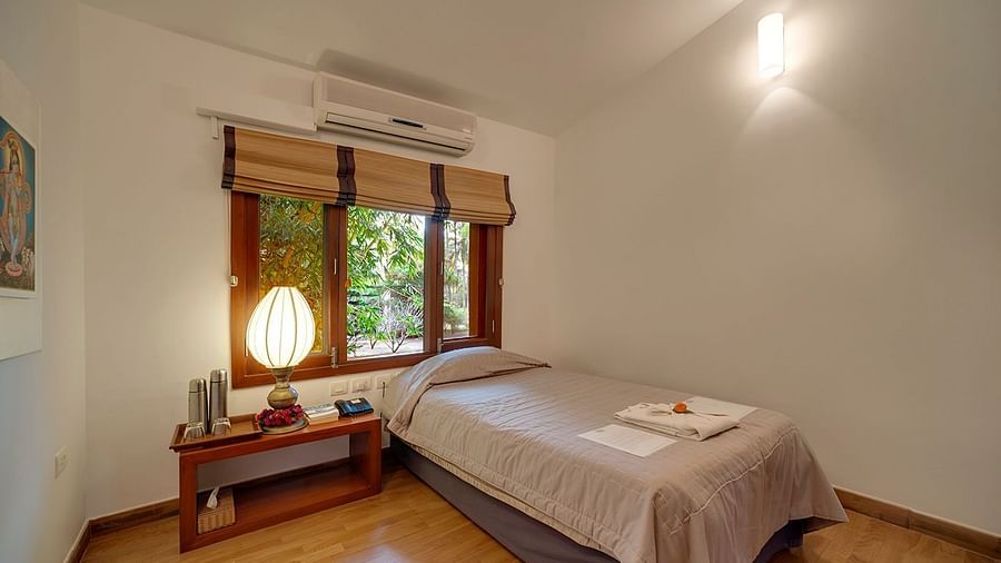 A bedroom with a low bed, a window with blinds, and a lamp - Shreyas Retreat