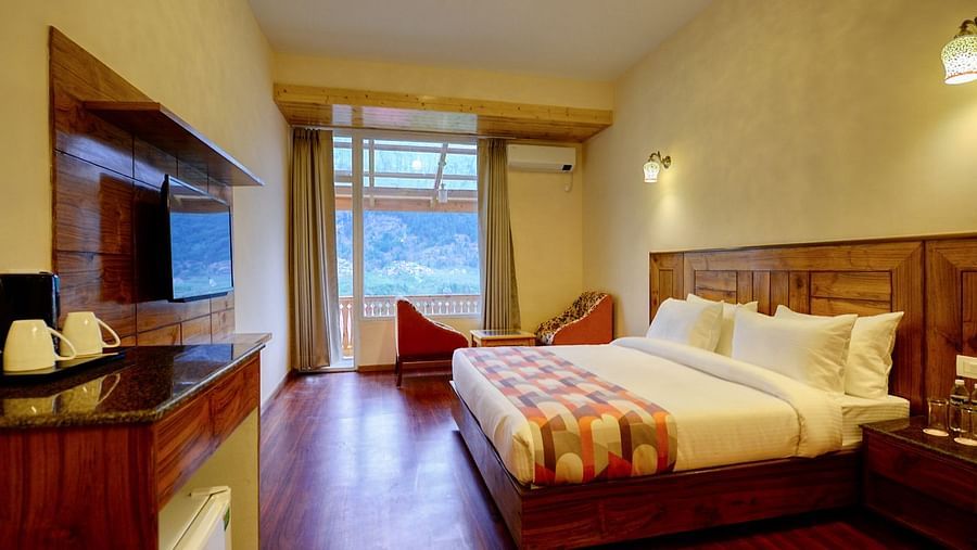 Well lit bedroom with a double bed and television - Clarks Inn Suites, Manali