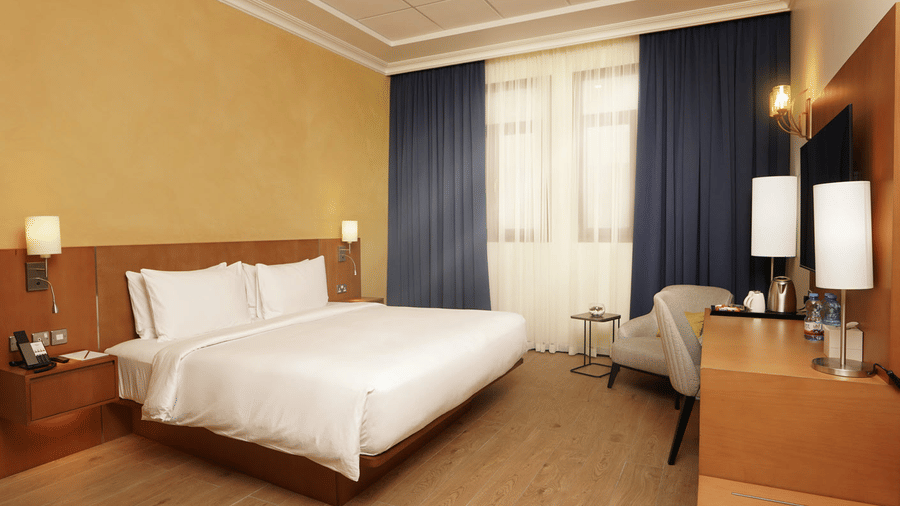Elegant Classic King Room featuring a plush king size bed, warm interiors, and modern comforts at La Maison Hotel in Doha, Qatar.