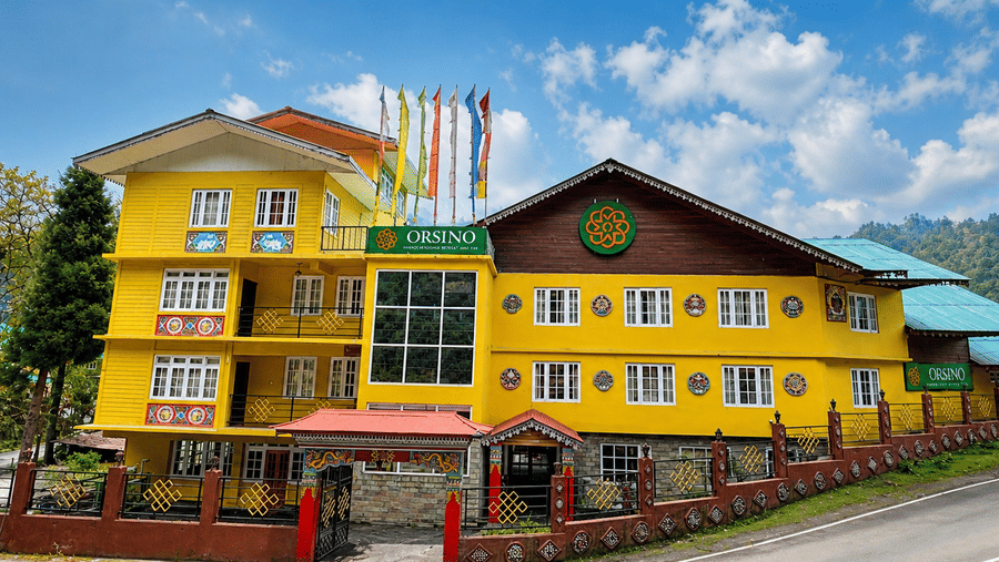 The front exterior of Orsino Khangri Karpo Retreat & Spa, Lachung under a clear sky showing the building name and architectural details from the street.