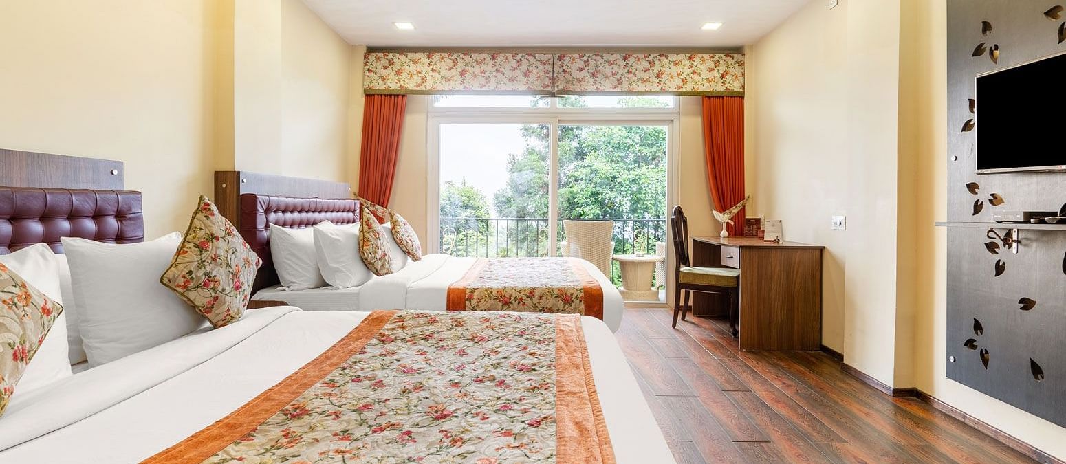 A room with twin beds and a balcony at Summit Barsana Resort & Spa, Kalimpong