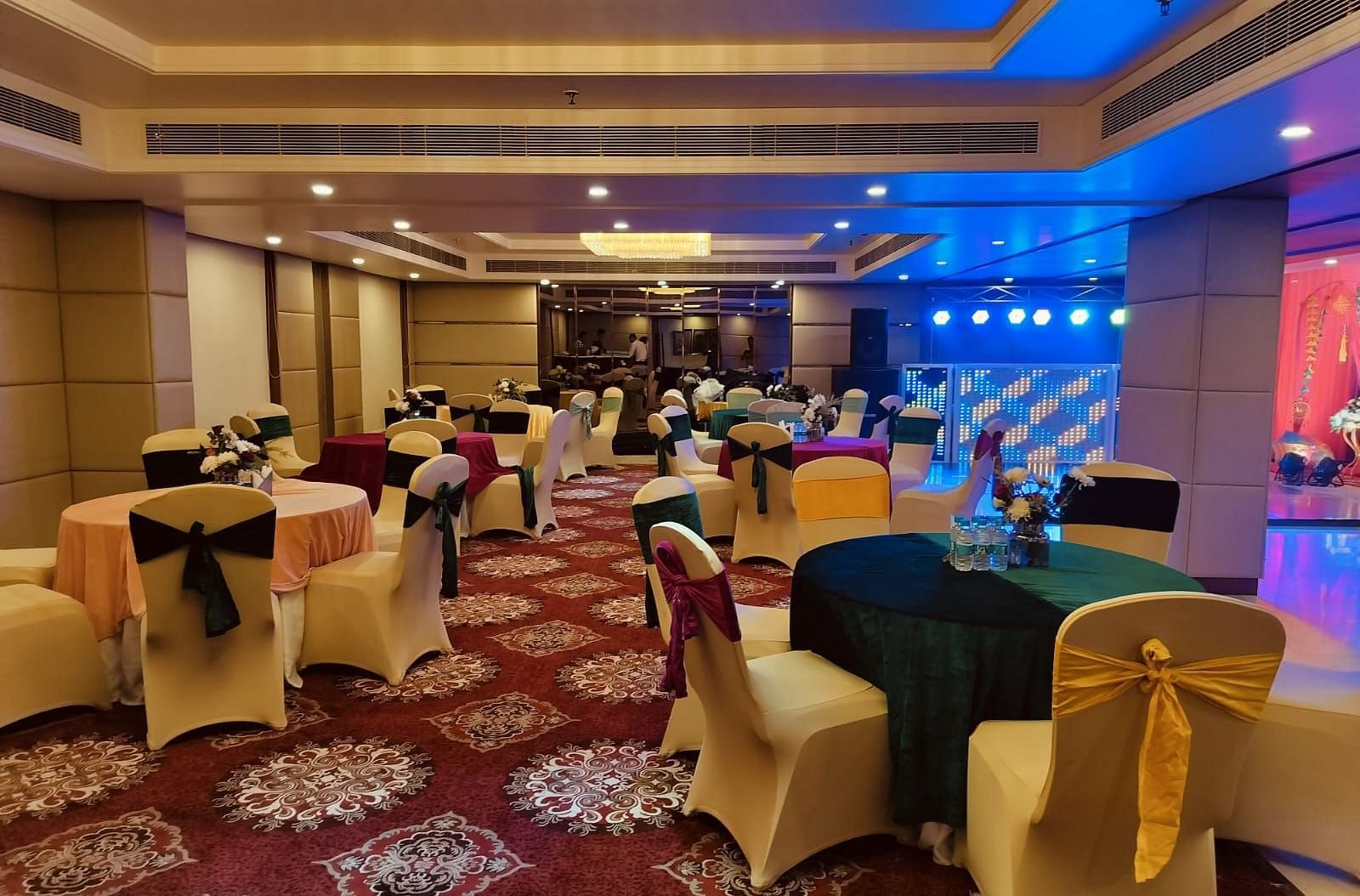 A beautiful banquet hall with carpet flooring and blue halogen lights lit up in the corner - Ramada by Wyndham, Ghaziabad, Vasundhara