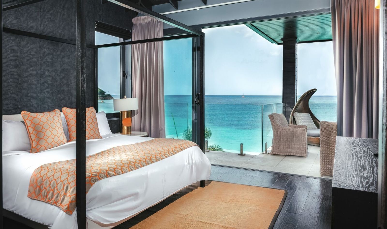 A double bed beside a floor to ceiling sliding glass door leading to a private beach.