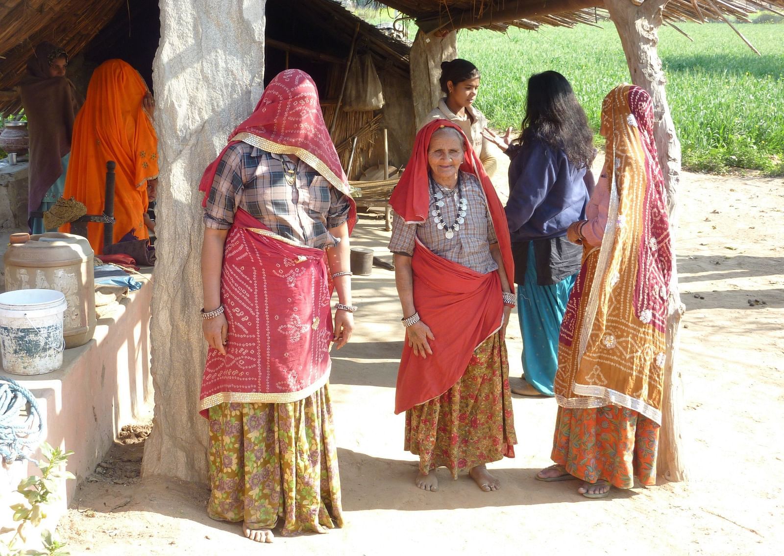 A group of Rajasthani women standing next to their house in the hot sun.