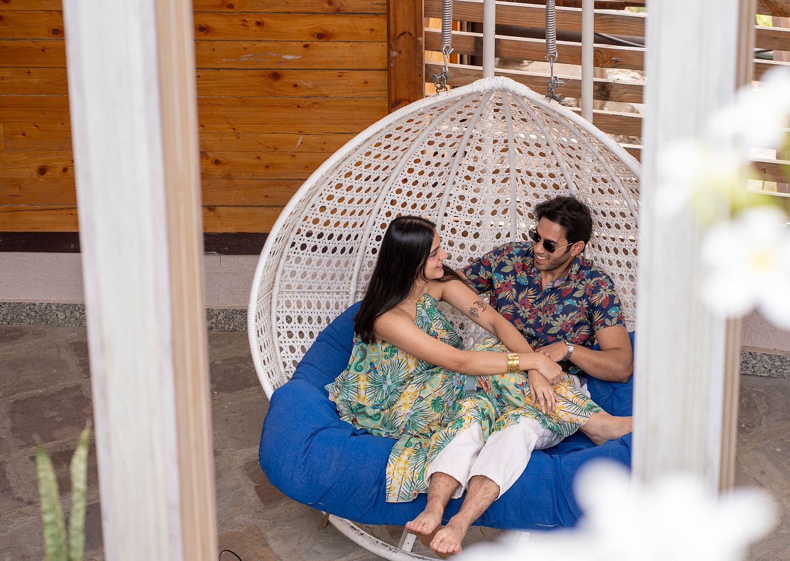 A man and a woman looking at each other and smiling in a swing.