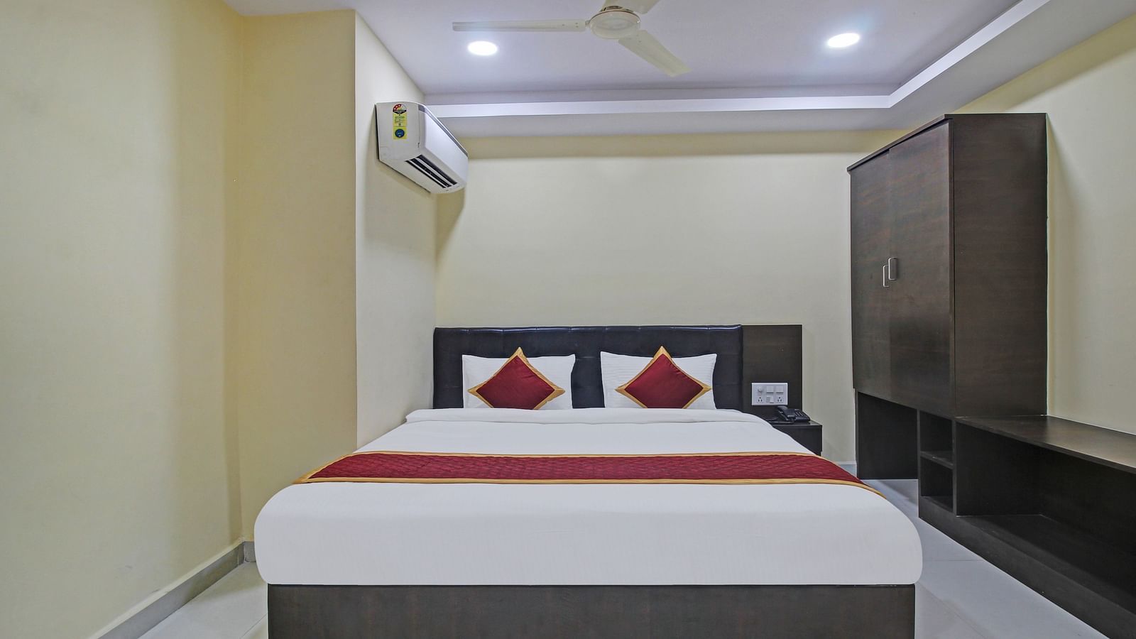 A hotel room featuring a double bed, storage cabinet, air conditioning, wardrobe, and a minimalist design with clean lines.