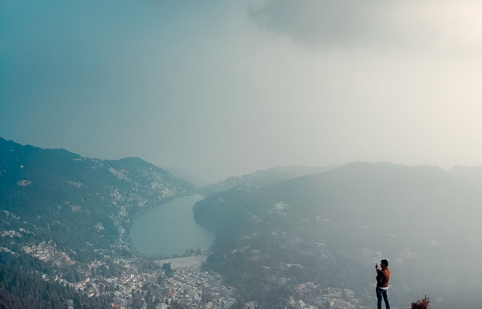 A wide shot of a person standing on a mountain peak