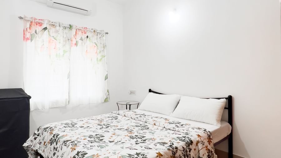 Bright bedroom with double bed and floral duvet at The Pinnacle, Electronic City.