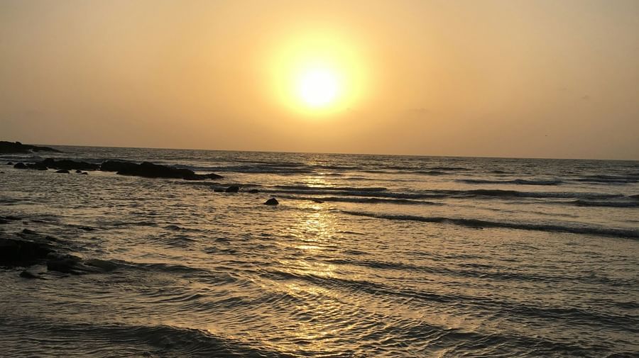 An overview of Aksa Beach with the sun setting in the background and waves crashing on the beach for the ideal Short Break Near Mumbai