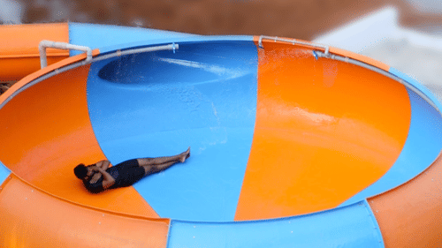 A person sliding down a large orange and blue bowl-shaped water slide at Black Thunder Water Theme Park.