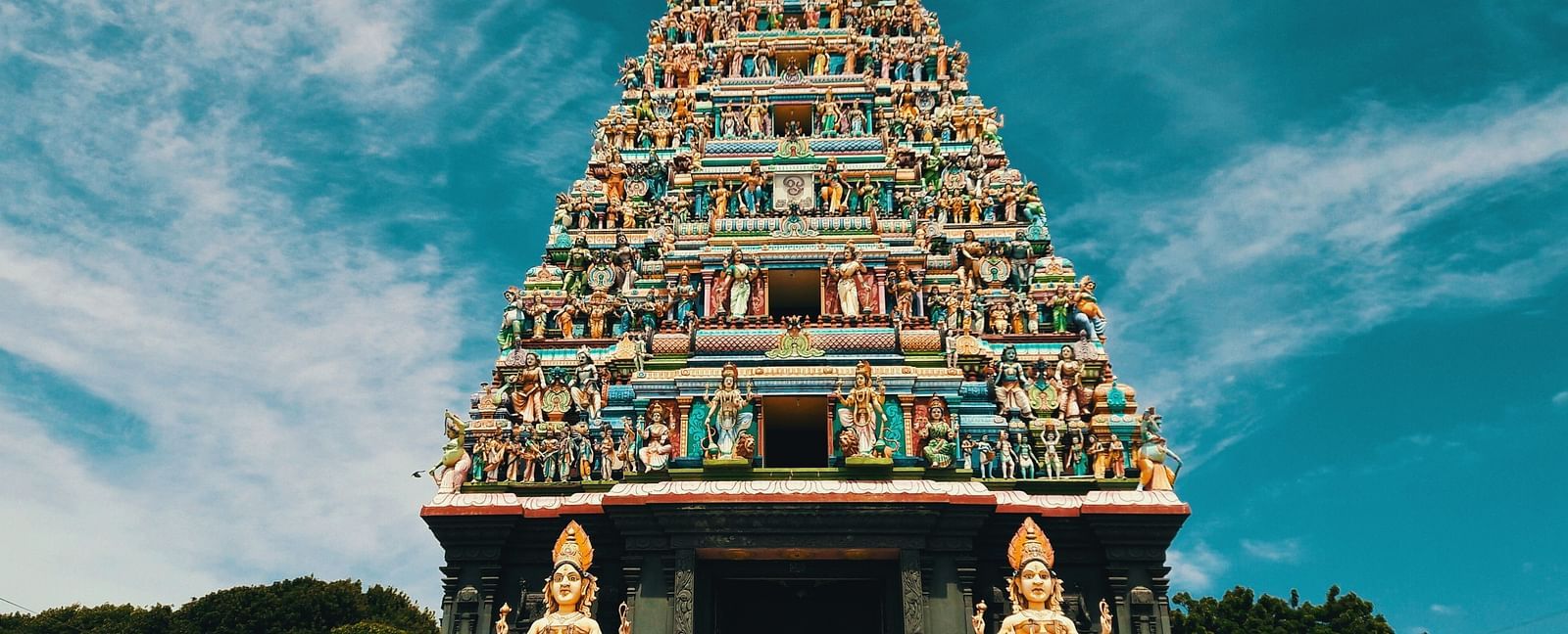 A temple with intricate carvings on its roof and two hindu deities on either side of the entrance.