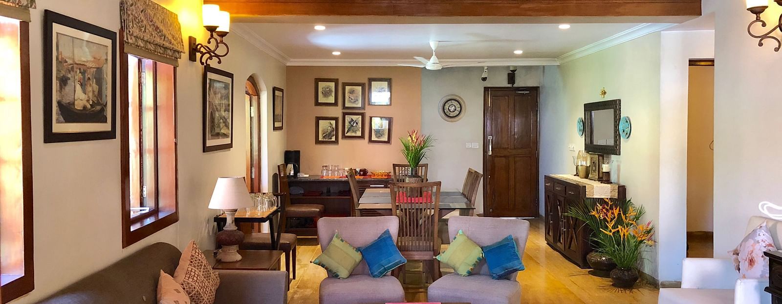 Living Area featuring a four seater sofa along with three couches behind which there is a six-seater dining table 